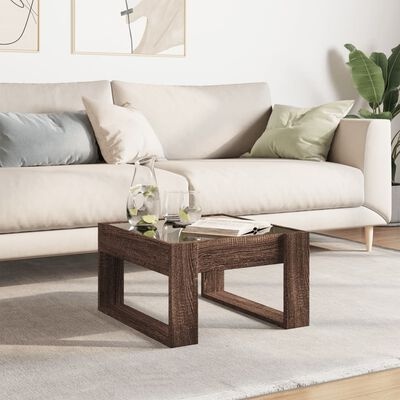 Mesa de centro de madeira com vidro em sala com sofá bege e almofadas coloridas.