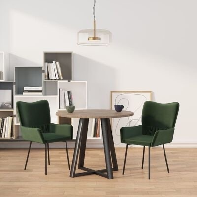 Conjunto de mesa redonda de madeira clara com duas cadeiras verdes e pernas pretas em sala com estantes e candeeiro suspenso