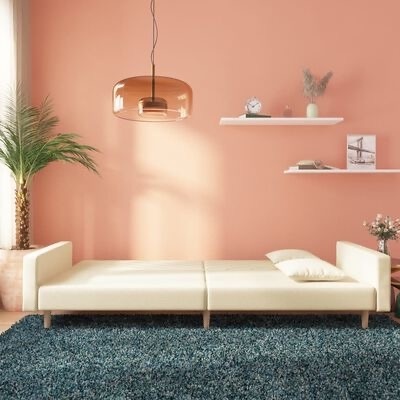 Sofá cama branco em sala com parede rosa, tapete azul, candeeiro âmbar, plantas e prateleiras brancas