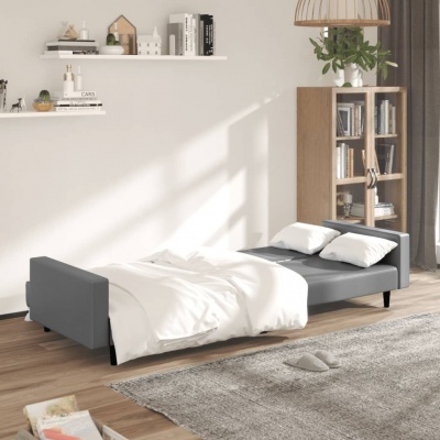 Cama de solteiro cinza escura com roupa branca, em sala com estante de madeira e prateleiras na parede