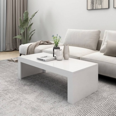 Mesa de centro branca retangular com decoração, sofá creme e tapete cinza numa sala moderna