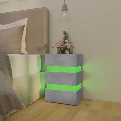 Mesa de cabeceira cinza com luz verde ao lado de cama e vaso de flores