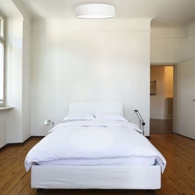 Quarto minimalista com cama de casal branca e iluminação natural