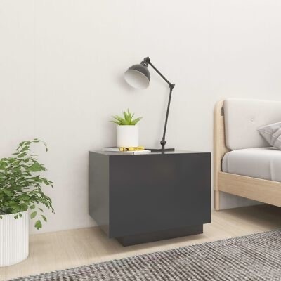 Mesa de cabeceira cinza escura com candeeiro, planta e livros ao lado de cama de madeira num quarto claro