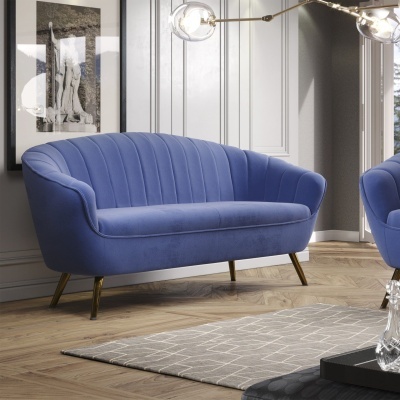 Sofá azul em veludo com pernas douradas numa sala com chão de madeira e decoração moderna.