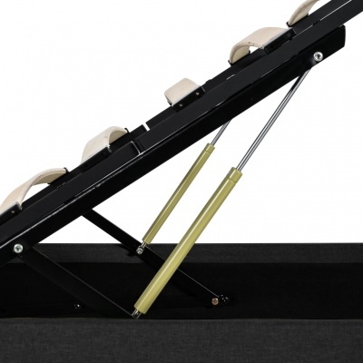 Estrutura inclinada de metal preto com almofadas bege e pistões gasosos dourados