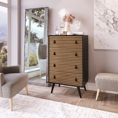 Cômoda de madeira preta e clara com quatro gavetas numa sala com espelho e decoração