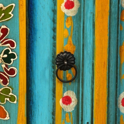 Porta de madeira colorida com puxador de ferro preto e pintura floral