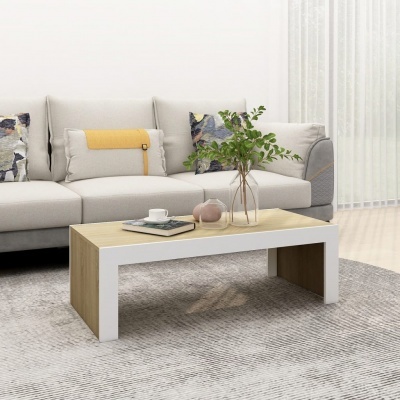 Mesa de centro retangular em madeira clara com decoração, sobre tapete cinza, em frente a sofá bege com almofadas coloridas