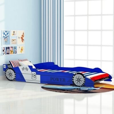Cama infantil em forma de carro de corrida azul, branco e vermelho junto a janela com cortinas e quadros na parede