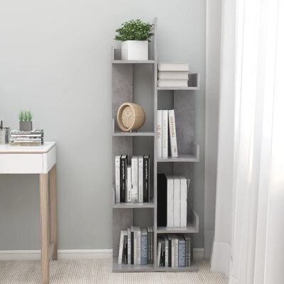 Estante vertical cinza claro com livros, relógio de madeira e vasos de plantas ao lado de secretária branca e parede cinzenta