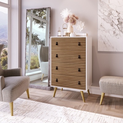 Comoda de madeira clara com frentes ripadas em quarto com cadeirões cinzentos e espelho grande