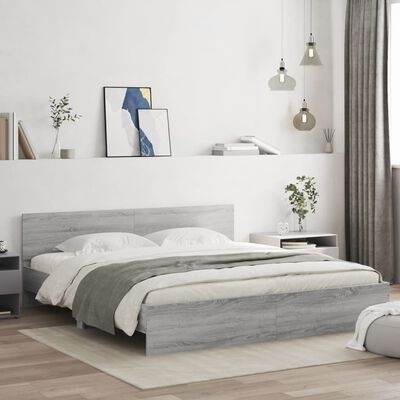 Cama de madeira clara com roupa de cama branca e cinza em quarto moderno com decoração minimalista.