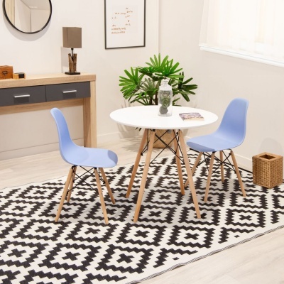 Conjunto de mesa redonda branca com cadeiras azuis em tapete geométrico preto e branco