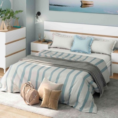 Quarto com cama branca com roupa de cama às riscas azuis e brancas e mobília branca com madeira clara