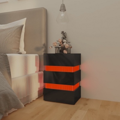 Mesa de cabeceira preta com faixas laranja iluminadas ao lado de cama com roupa cinza e branca
