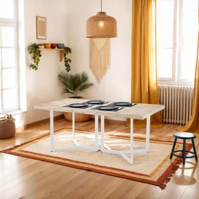 Mesa de jantar em madeira clara com pernas brancas, tapete bege com borda laranja, cortinas amarelas e lâmpada de palha pendente