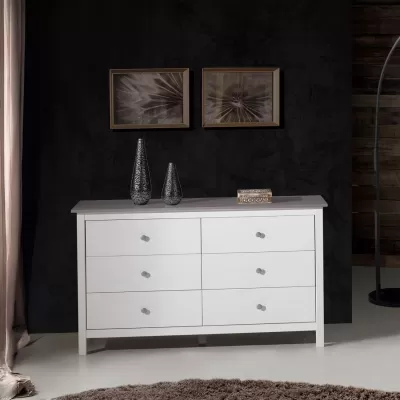 Cómoda branca de madeira com seis gavetas e decoração de vasos e caixa decorativa