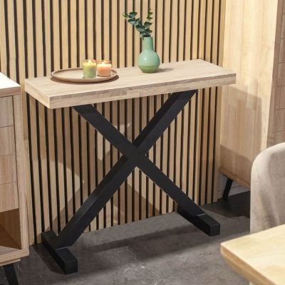 Mesa de consola de madeira clara com base preta em X e decoração com velas e vaso