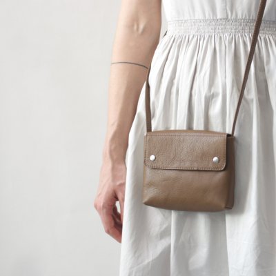 Mala pequena castanha em pele com alça fina e vestido branco