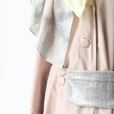 Pochete prateada com textura metálica usada sobre casaco bege claro e lenço cinza e amarelo