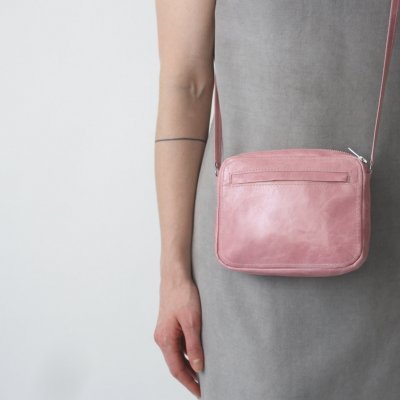 Mala pequena de couro rosa com alça comprida usada ao ombro