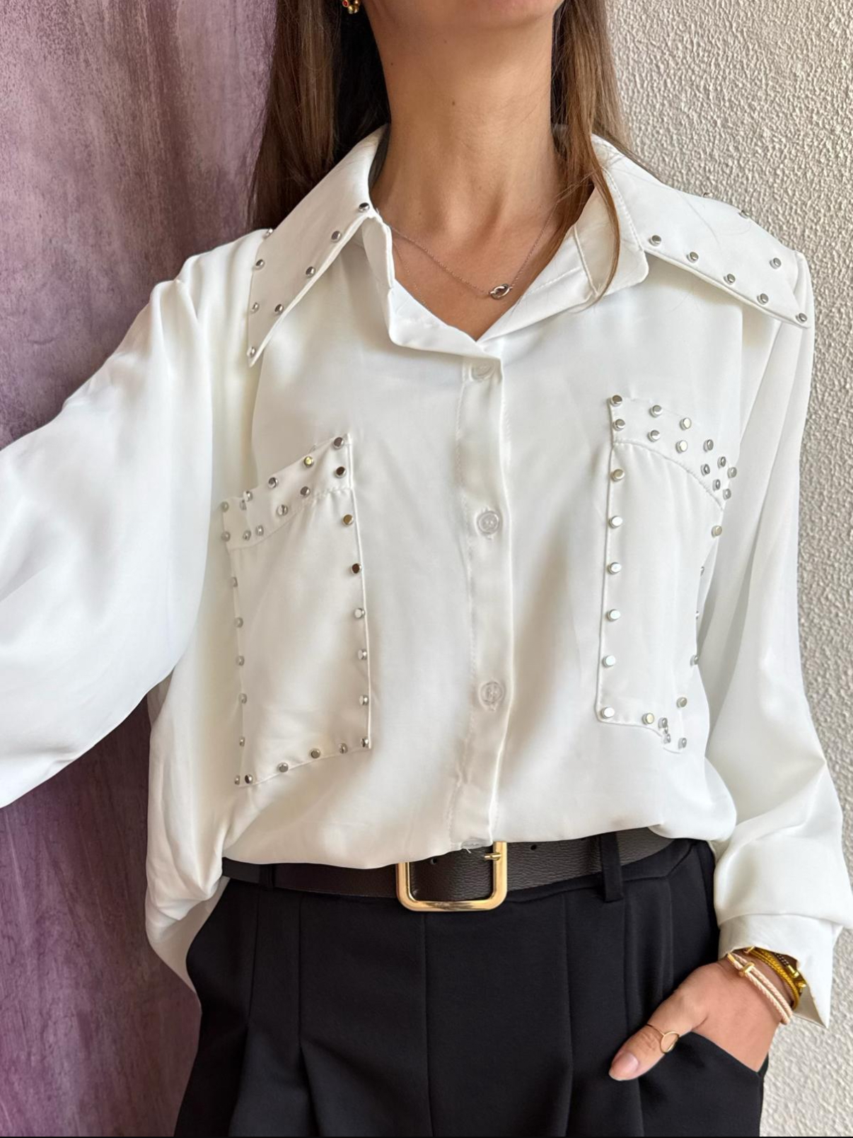 Blusa branca com tachas prateadas nos bolsos e colarinho junto com calças e cinto preto