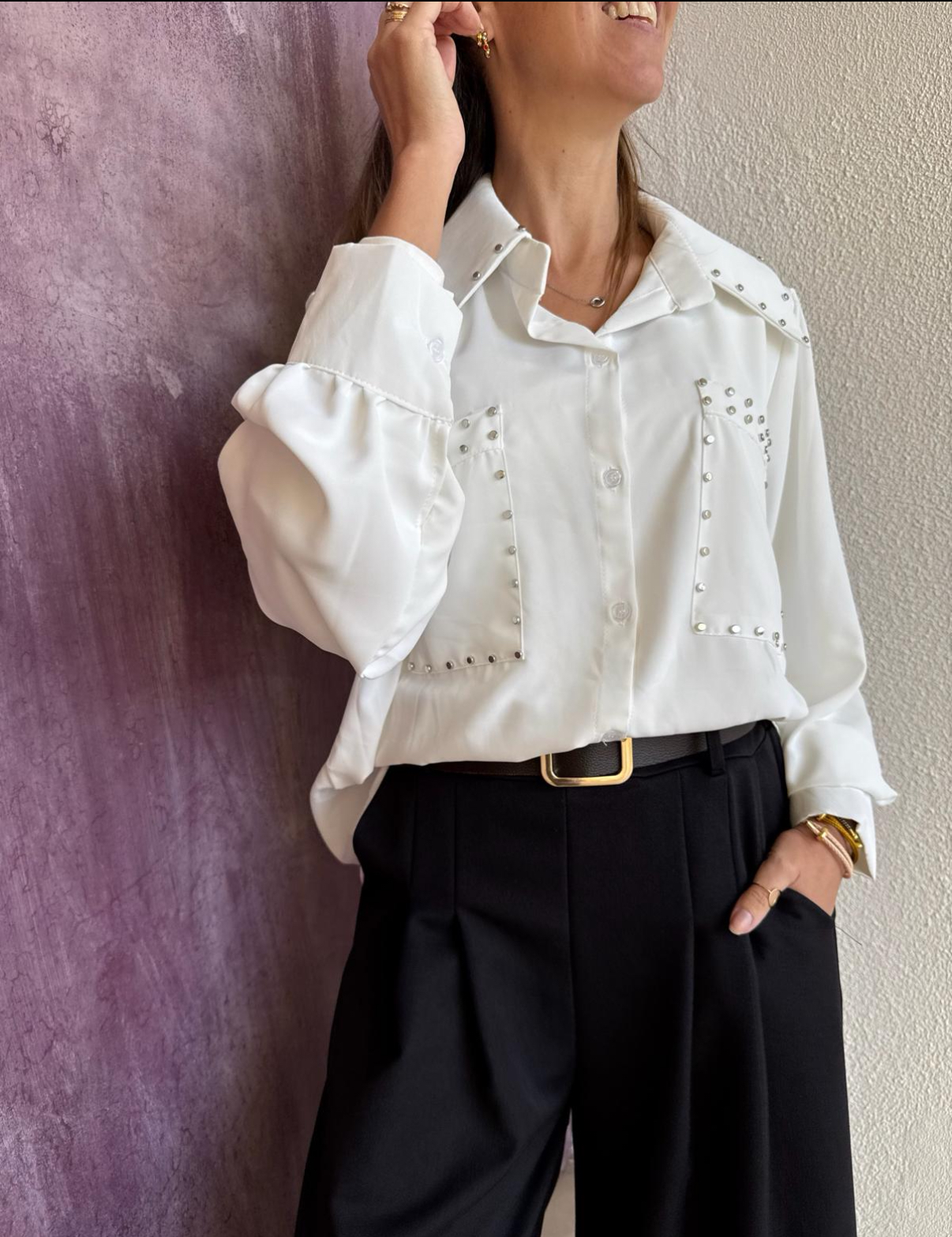 Blusa branca com tachas prateadas e calças pretas com cinto dourado