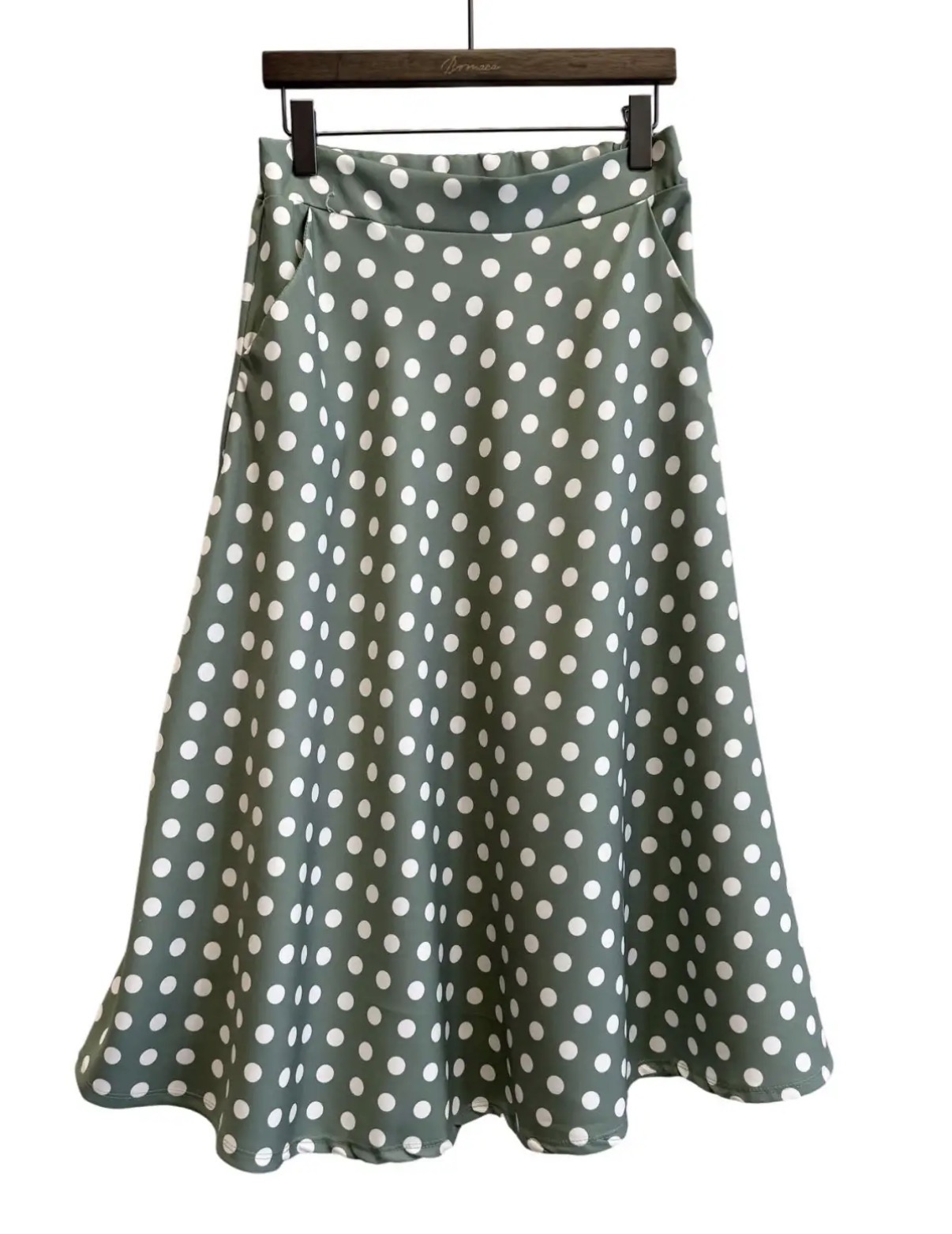 Saia verde com bolinhas brancas em cabide de madeira