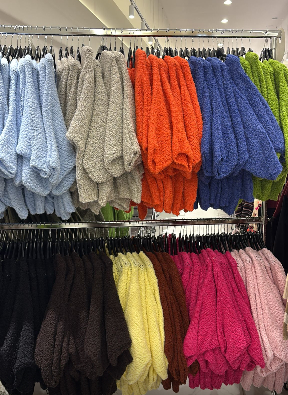 Roupas de malha felpuda coloridas penduradas em cabides em prateleiras de loja