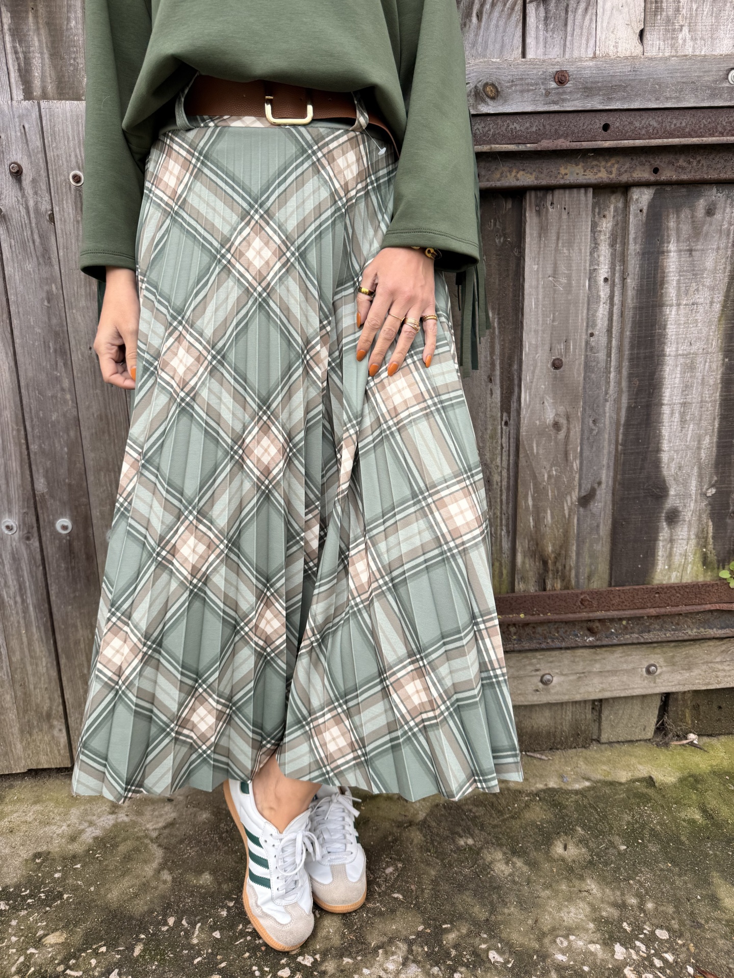 Saia plissada xadrez verde e bege com ténis brancos e cinto castanho