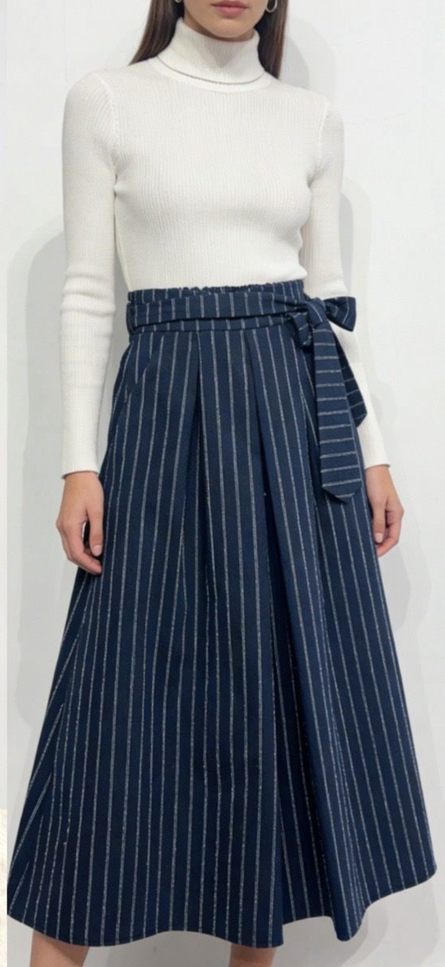 Conjunto feminino com top branco de gola alta e saia midi azul às riscas com cinto.