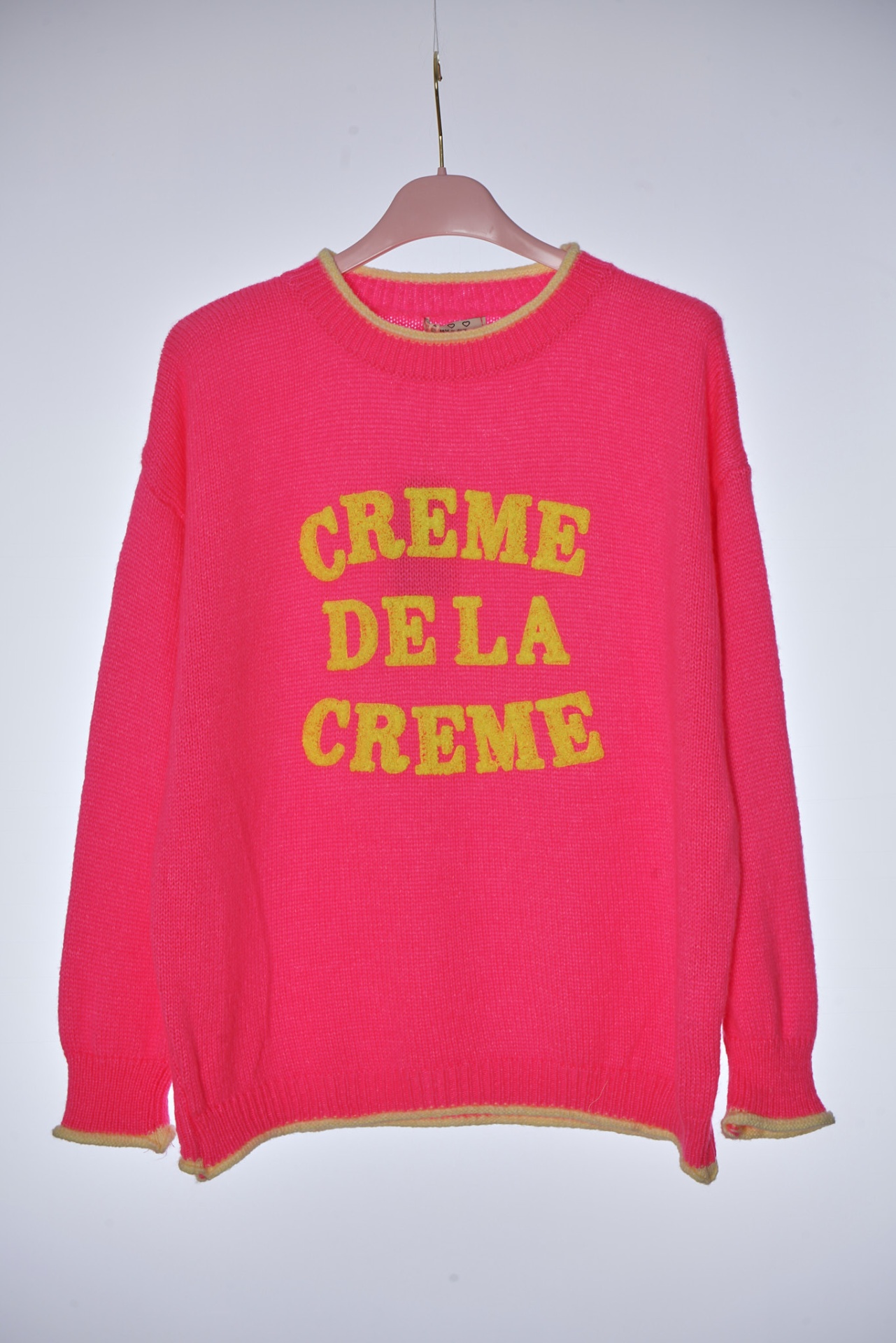 Camisola de malha rosa com texto amarelo CREME DE LA CREME