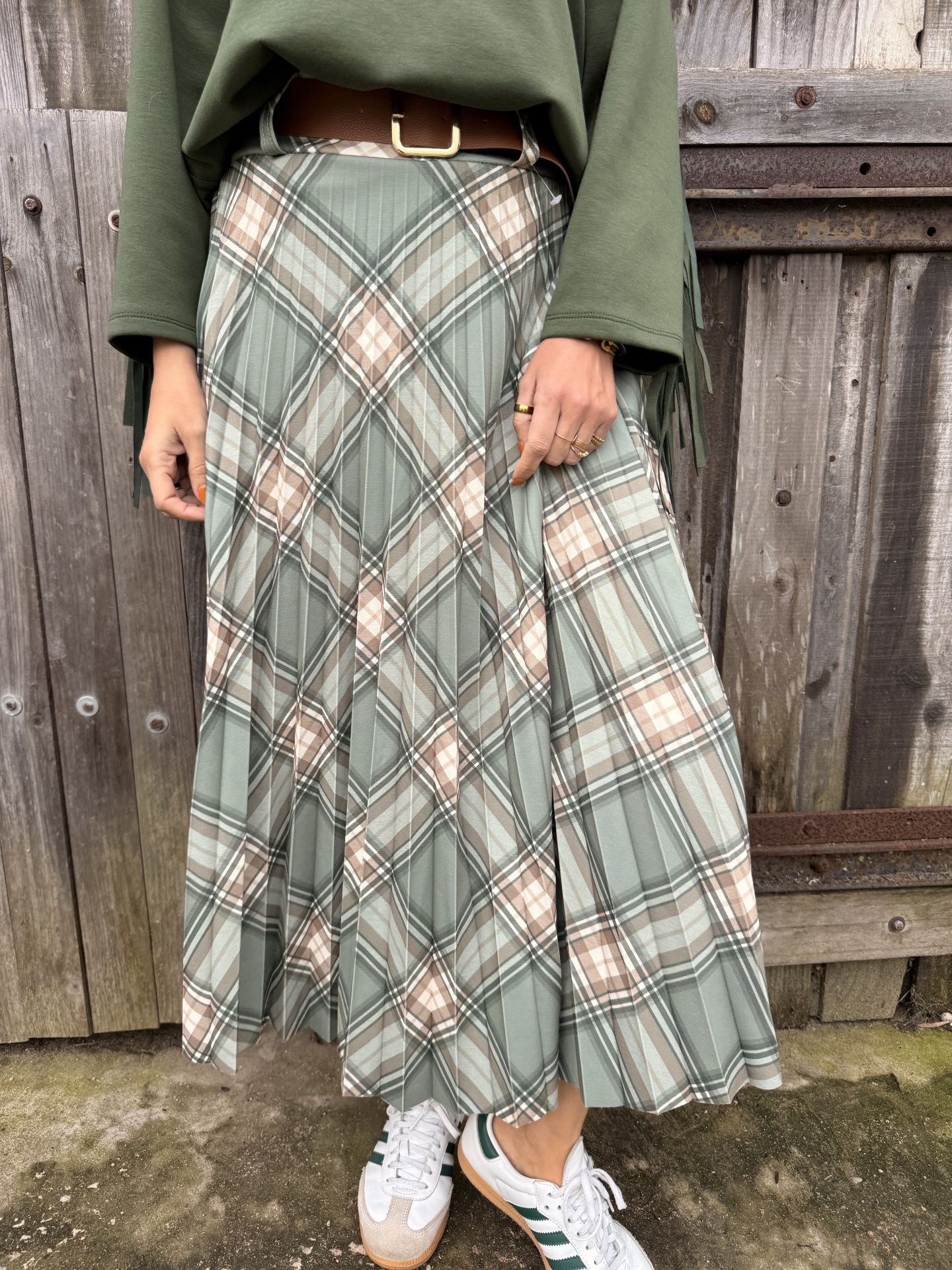 Saia plissada xadrez verde e bege com cinto castanho e ténis brancos verdes