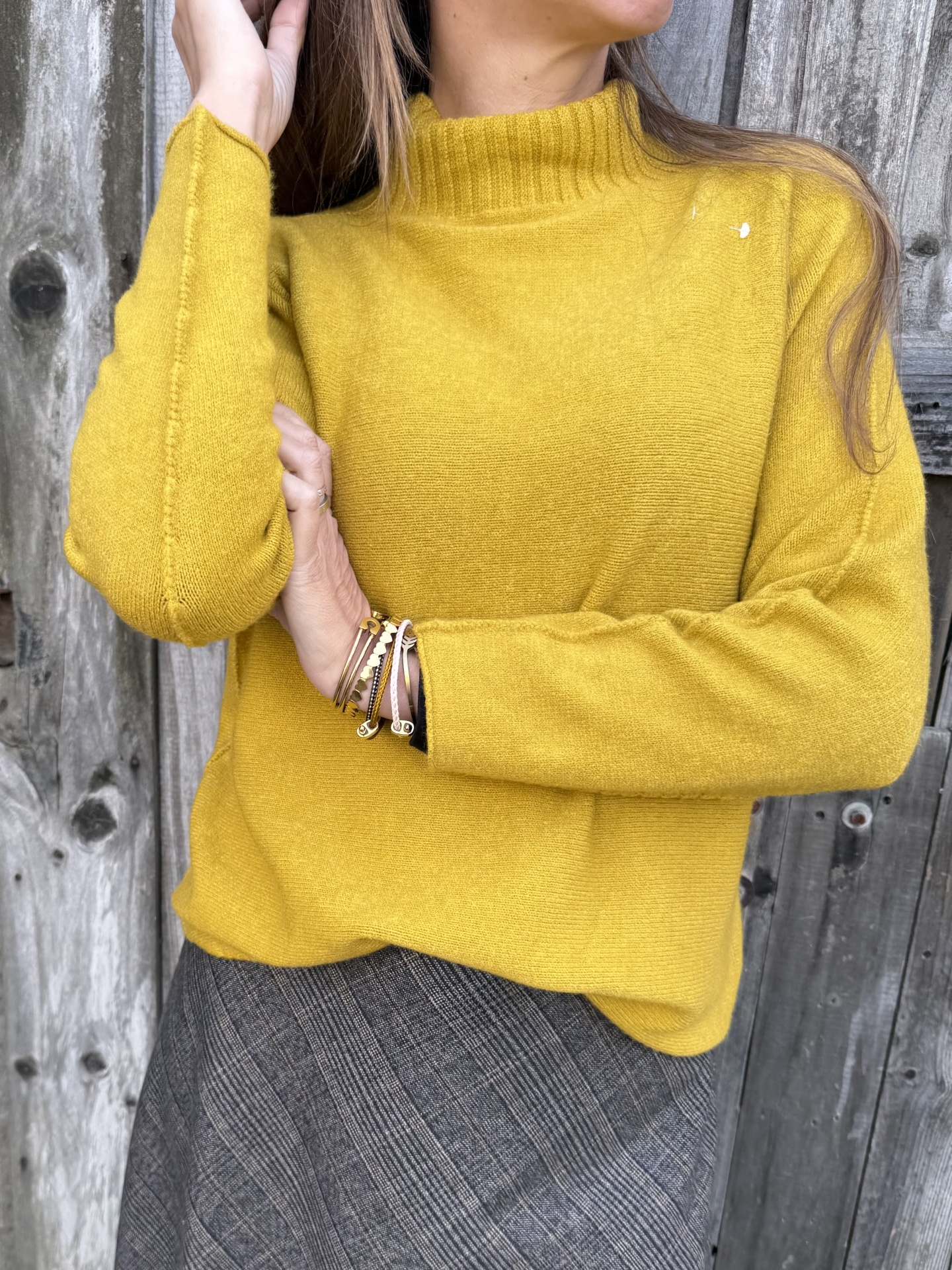 Casaco amarelo mostarda de malha com gola alta e saia xadrez cinzenta