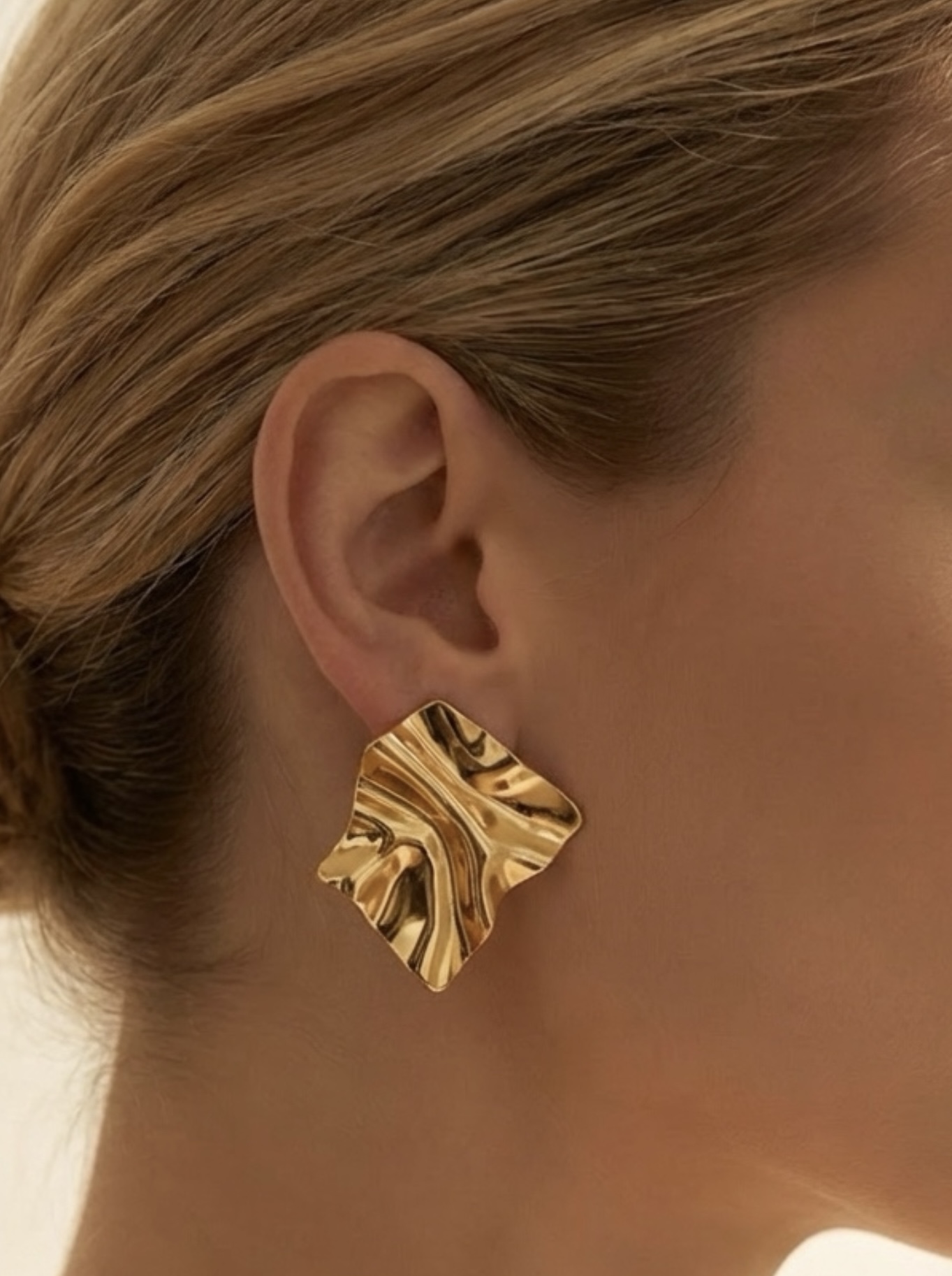 Brinco dourado ondulado em formato irregular quadrado na orelha