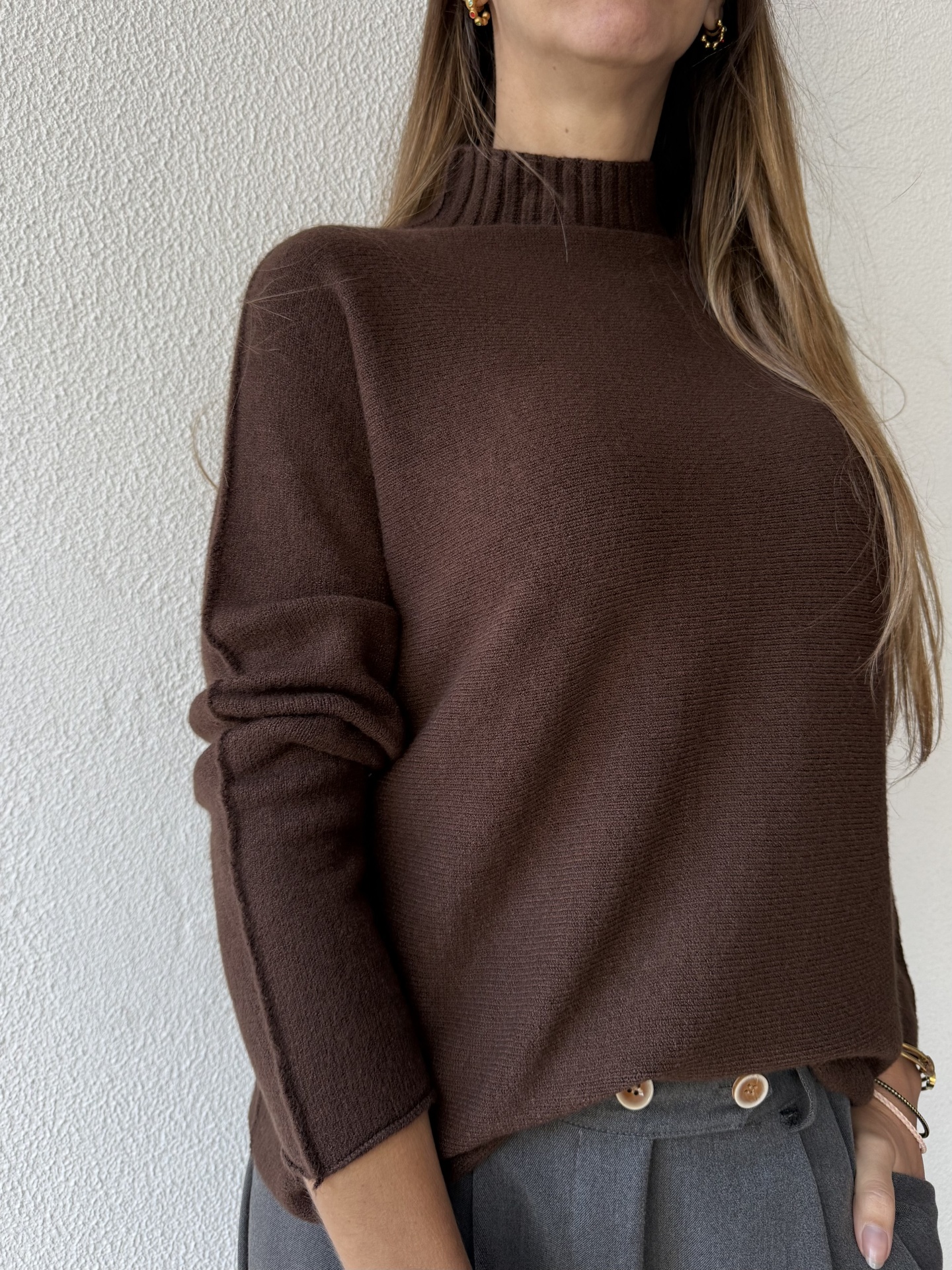 Camisola castanha de malha com gola alta e mangas compridas, calças cinzentas com botões