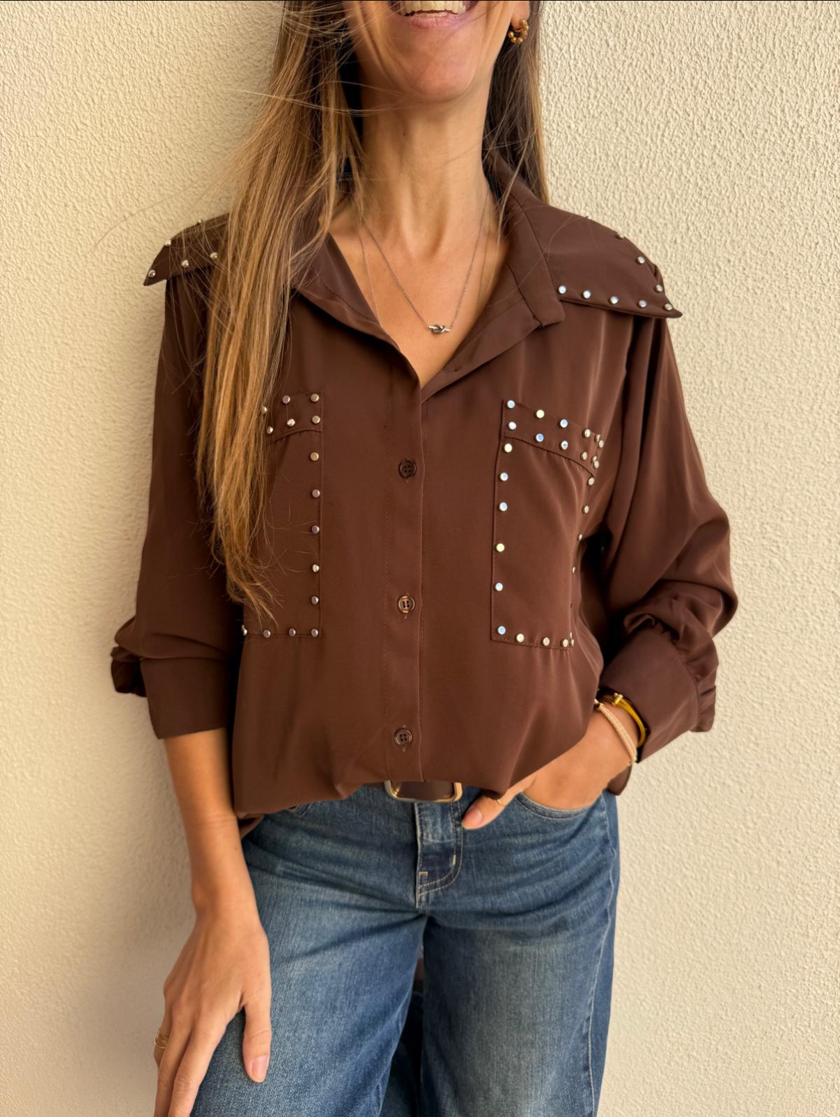 Camisa castanha com tachas e calças de ganga azuis