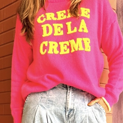 Camisola rosa de malha com texto amarelo e calças de ganga largas brancas