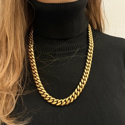 Colar dourado grosso sobre camisola preta de gola alta