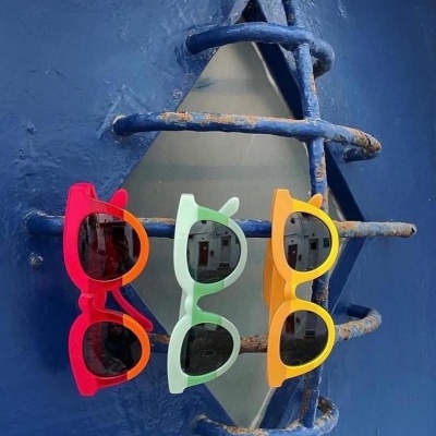 Três óculos de sol coloridos pendurados em grades azuis com ferrugem