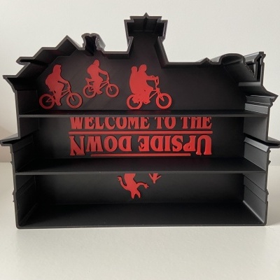 Estante preta em forma de casa com prateleiras e texto vermelho