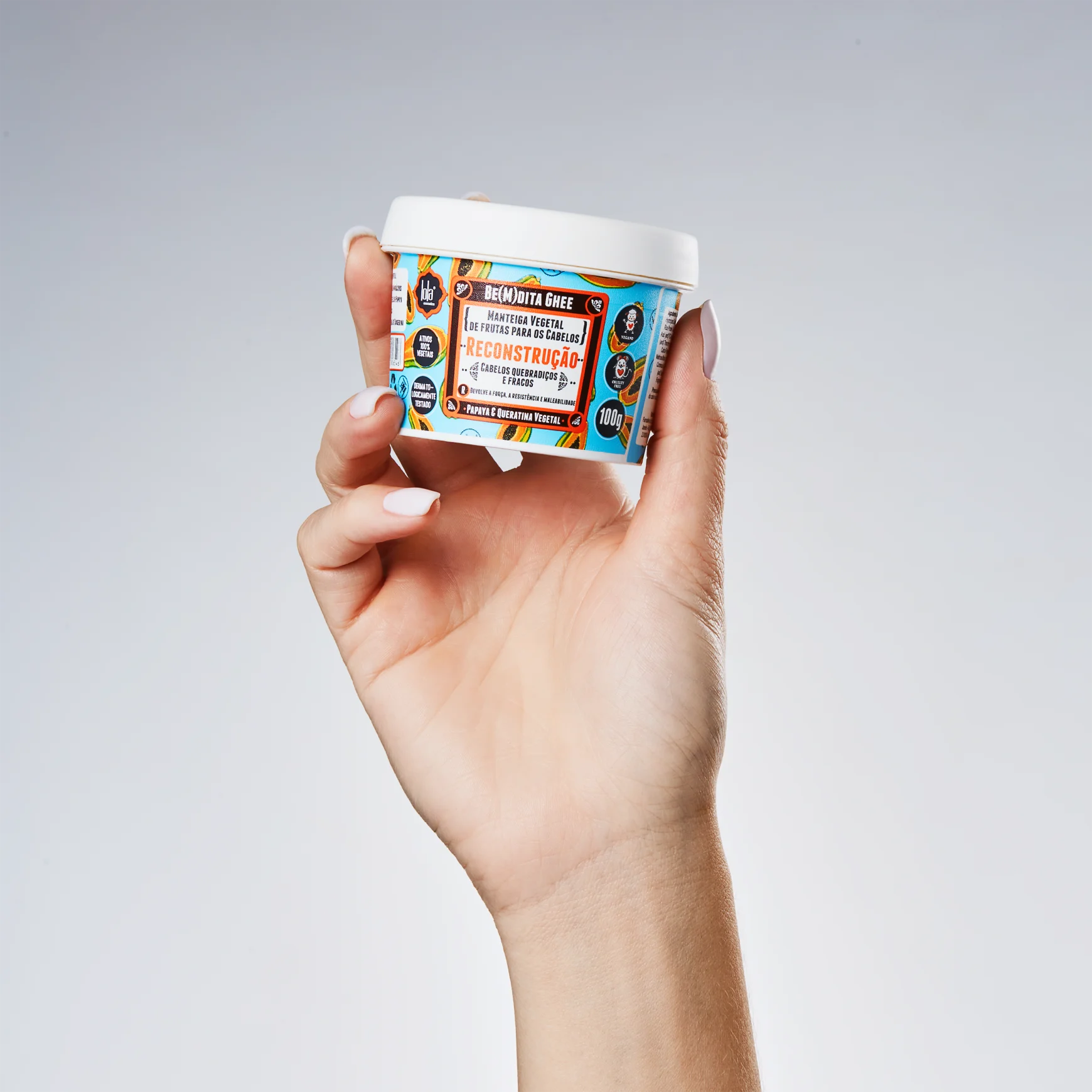 Mão a segurar embalagem branca com rótulo colorido de produto de cuidado