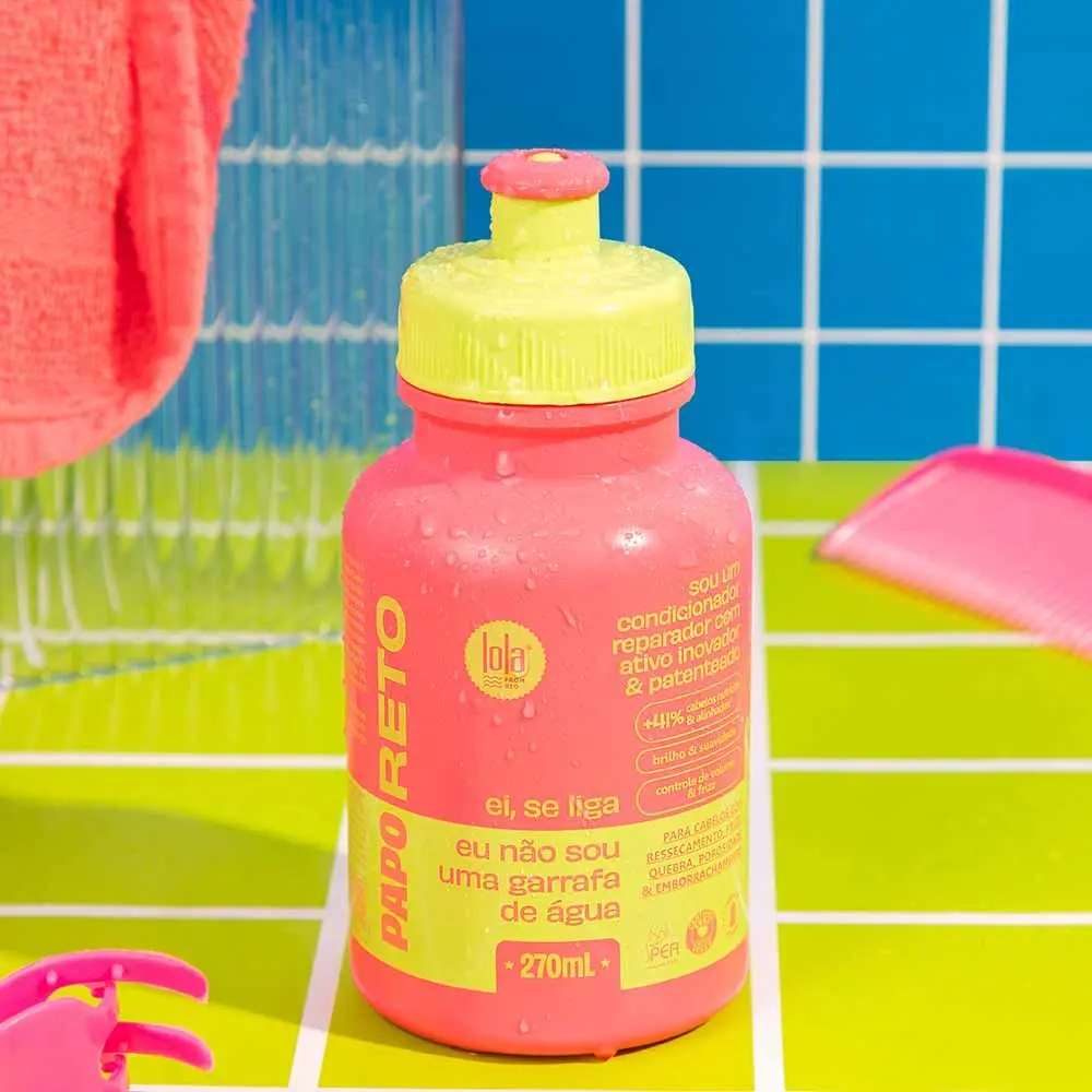 garrafa desportiva rosa e amarela sobre superfície verde e fundo azul