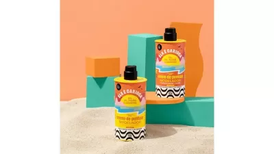 Dois frascos amarelos de creme de pentear com rótulos coloridos sobre areia e blocos coloridos ao fundo