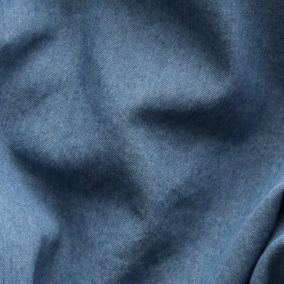 Close-up de tecido de ganga azul com textura diagonal e dobras suaves