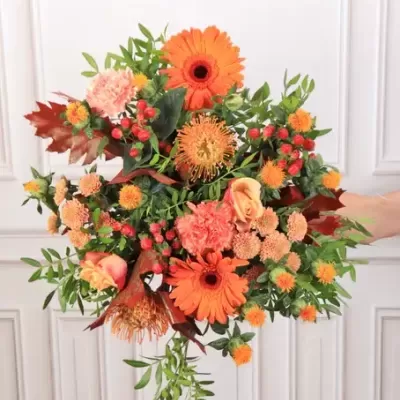 Arranjo floral laranja com várias flores e folhas verdes
