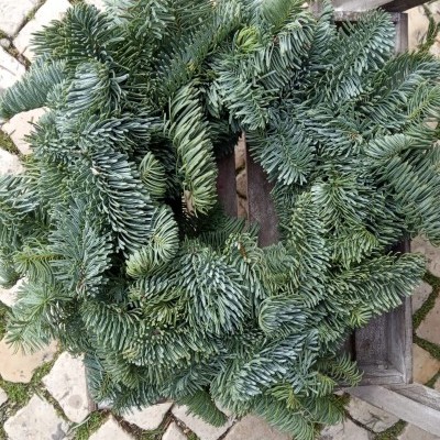 Coroa de Natal de ramos verdes de pinheiro sobre cadeira de madeira e chão de pedras