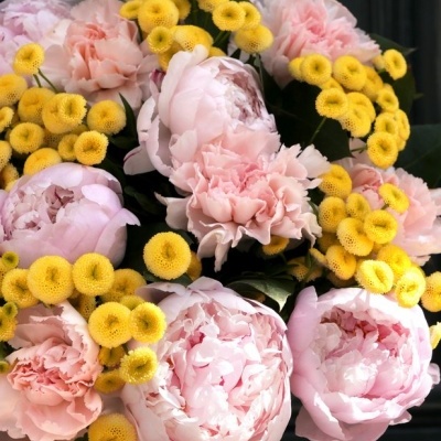 Bouquet de peónias rosa e flores amarelas redondas com folhagem verde