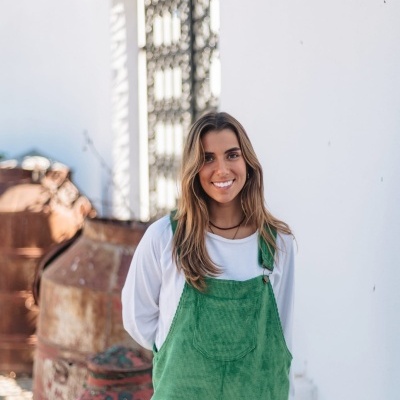 Jovem com macacão verde em espaço exterior perto de latas de tinta